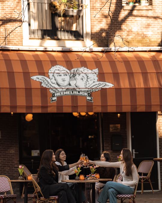 Guests toasting on the terrace under the Heemelrijck cherub logo
