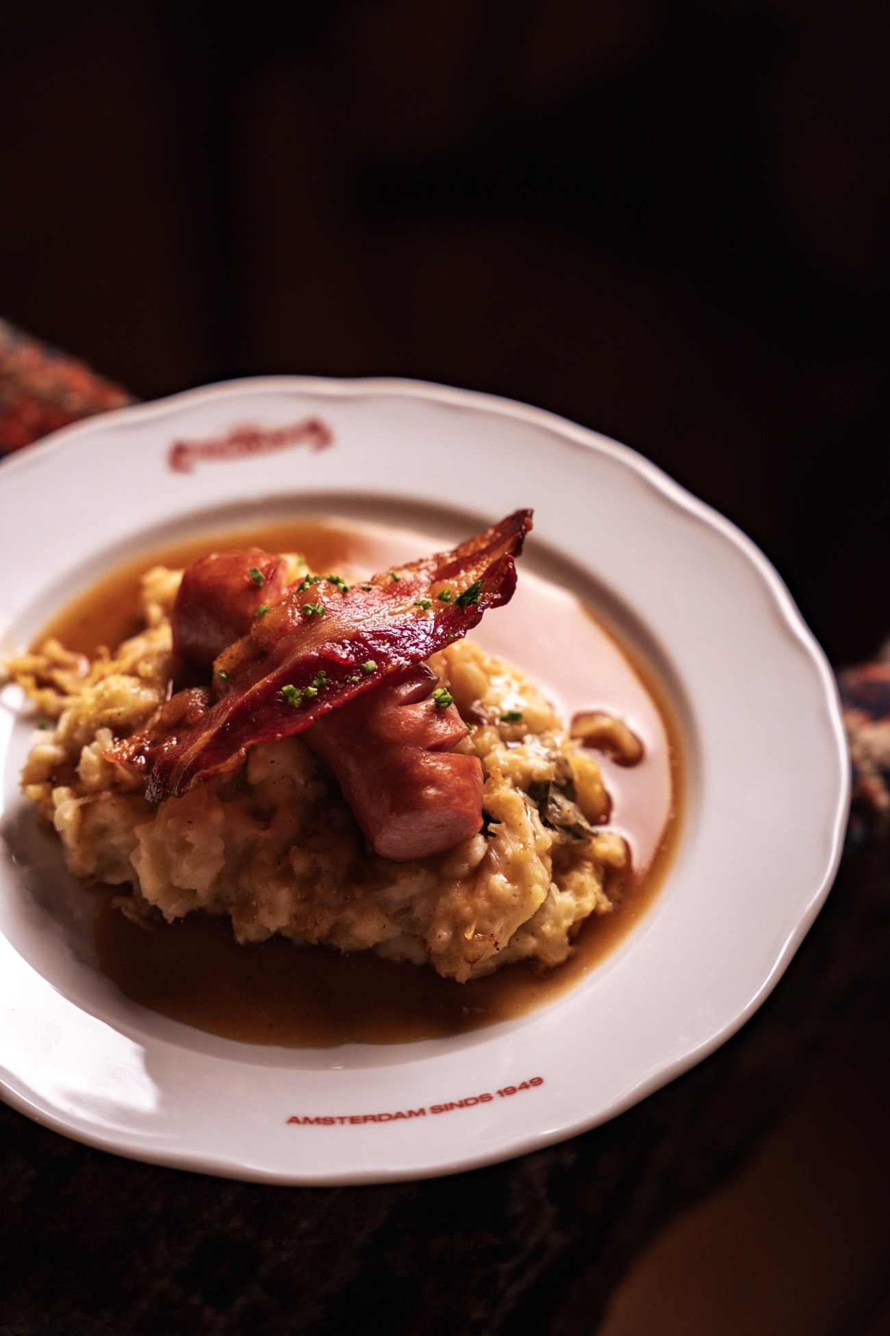 Stamppot with smoked sausage and crispy bacon on a Heemelrijck plate, Amsterdam since 1949